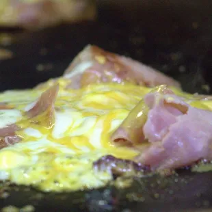 a ham and cheese pizza being cooked