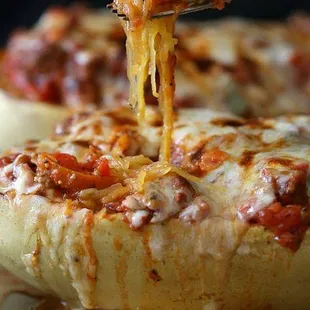 a fork lifting a piece of cheese from a stuffed eggplant