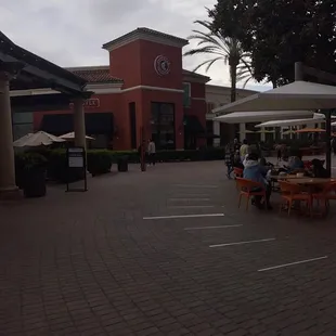 the outside of a restaurant with tables and umbrellas