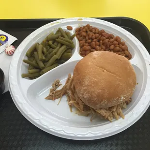 BBQ pulled chicken sandwich with baked &amp; green beans.