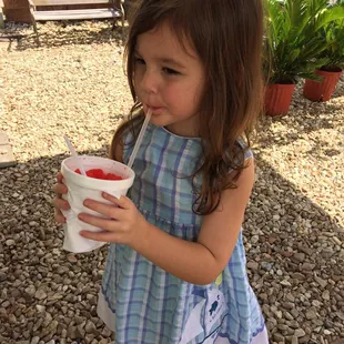 a young girl holding a cup of ice cream