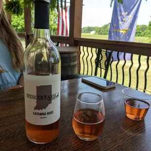 a woman sitting at a table with a bottle of wine