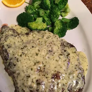 a piece of steak with gravy and broccoli