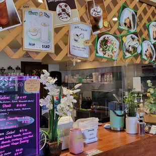 a coffee shop counter with a menu on the wall
