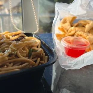a bowl of noodles and a container of chicken