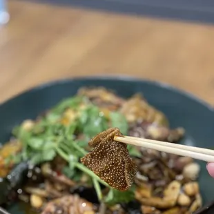 a person holding chopsticks over a bowl of food