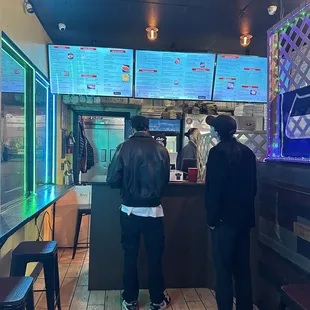 two people standing at a counter in a restaurant