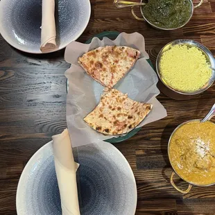 a wooden table with plates and bowls of food