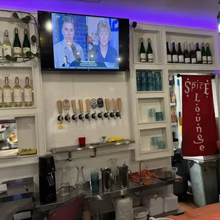 a bar with a television and wine glasses on the wall