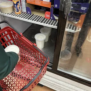 a person holding a basket in front of a refrigerator