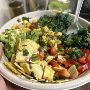 Coconut curry bowl with mango salsa, red bell peppers, kale lettuce, avocado, and plantain chips
