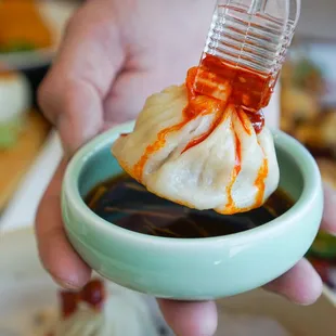 a person dipping sauce into a bowl of food