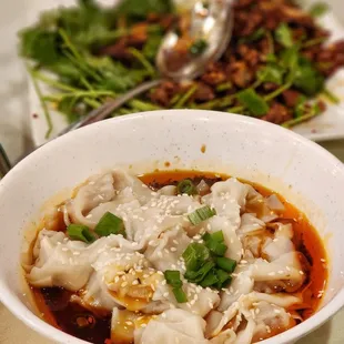 a bowl of dumplings and a plate of greens