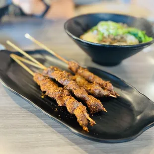 skewered meat on a black plate