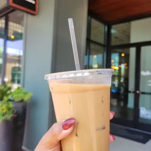 a hand holding a cup of iced coffee