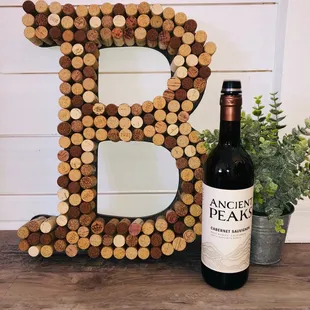 a bottle of wine next to a wine cork letter