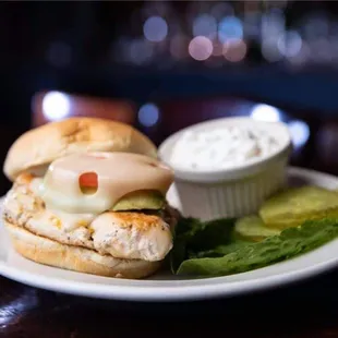 a chicken sandwich with a side of pickles