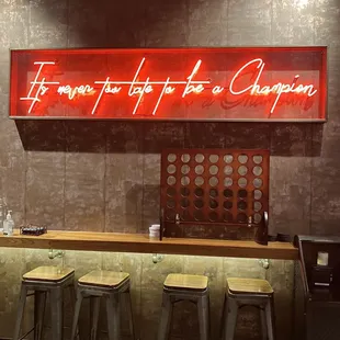 a bar with stools and a neon sign