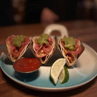 a plate of tacos with salsa and guacamole