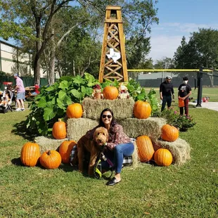 a woman and her dog in front of a pumpkin display