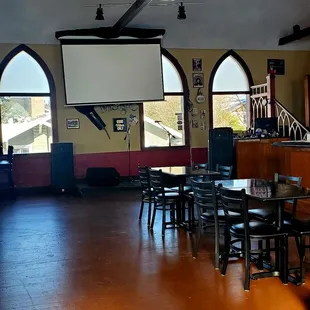 a large room with tables and chairs and a projector screen