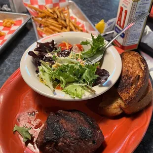 Sirloin steak dinner with house salad and some delicious seasoned fries.