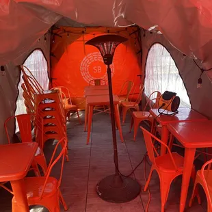 the inside of a tent with tables and chairs