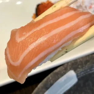 a piece of sushi being held by a pair of chopsticks
