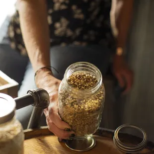 a person pouring grain into a jar