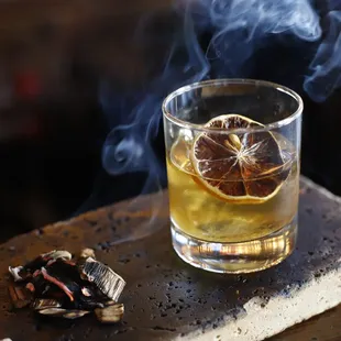 a glass of alcohol with a slice of orange in it