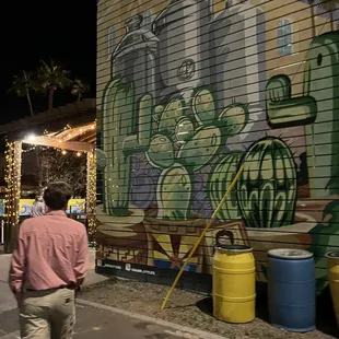 a man walking in front of a mural