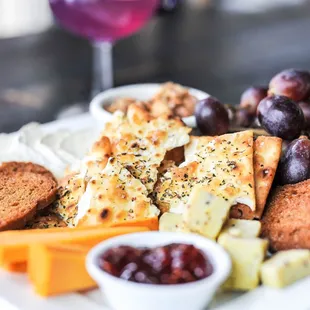 a plate of cheese, crackers, grapes, and bread