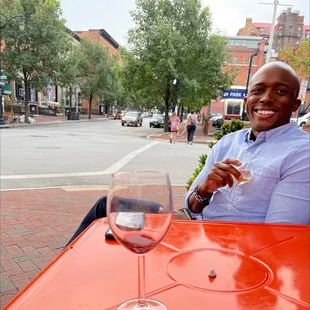 a man sitting at a table with a glass of wine