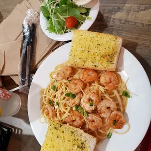 a plate of pasta with shrimp and garlic bread