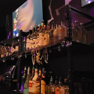 a shelf of liquor bottles and liquor glasses