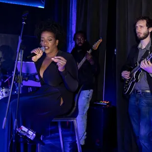 a woman in a black dress singing into a microphone