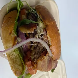 a hamburger with onions, lettuce, and bacon
