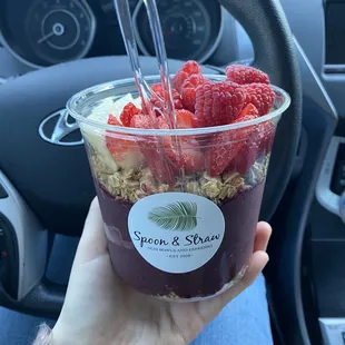 Açaí bowl with toppings of granola, banana, strawberry, and raspberry.