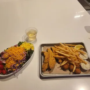 Cobb salad and fish plate with a glass of wine.