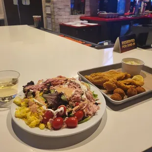 Egg, lettuce, ham, and more plus fish. Glass of wine.