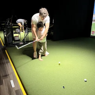 Brother showing him how to golf.