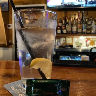 a glass of water with a lemon slice and a bar in the background