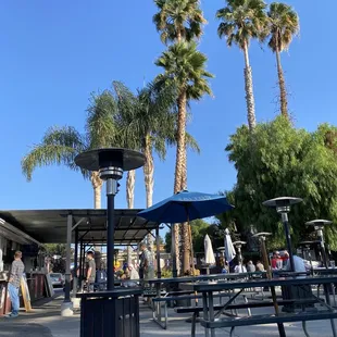 a group of people at a park with tables and umbrellas