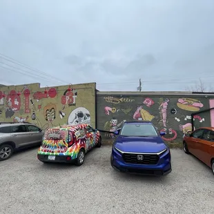 cars parked in front of a mural
