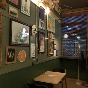 a table and chairs in front of a wall full of pictures
