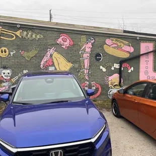 two cars parked in front of a mural
