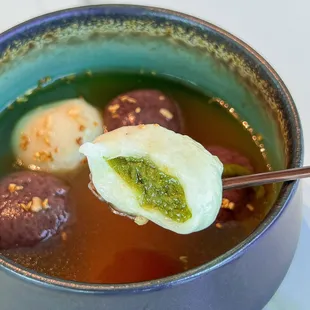 a ladle of soup with meatballs