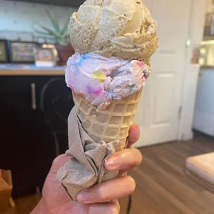 a hand holding a cone of ice cream