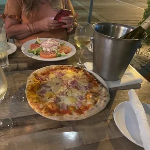 Hawaiian pizza and salad with a bottle of wine