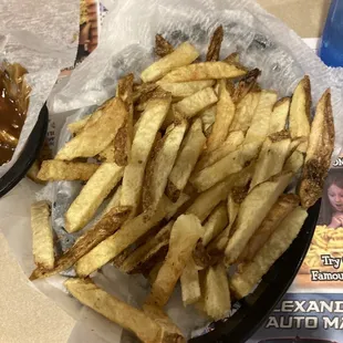 a basket of french fries and a bowl of barbecue sauce